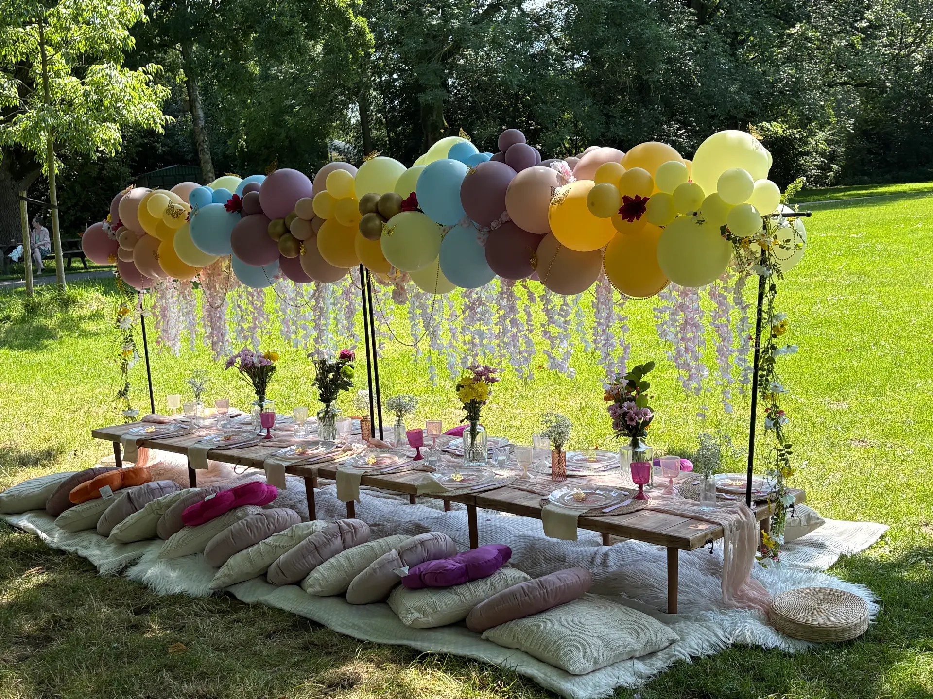 Colourful Mini Munchkins garden picnic beneath a balloon canopy