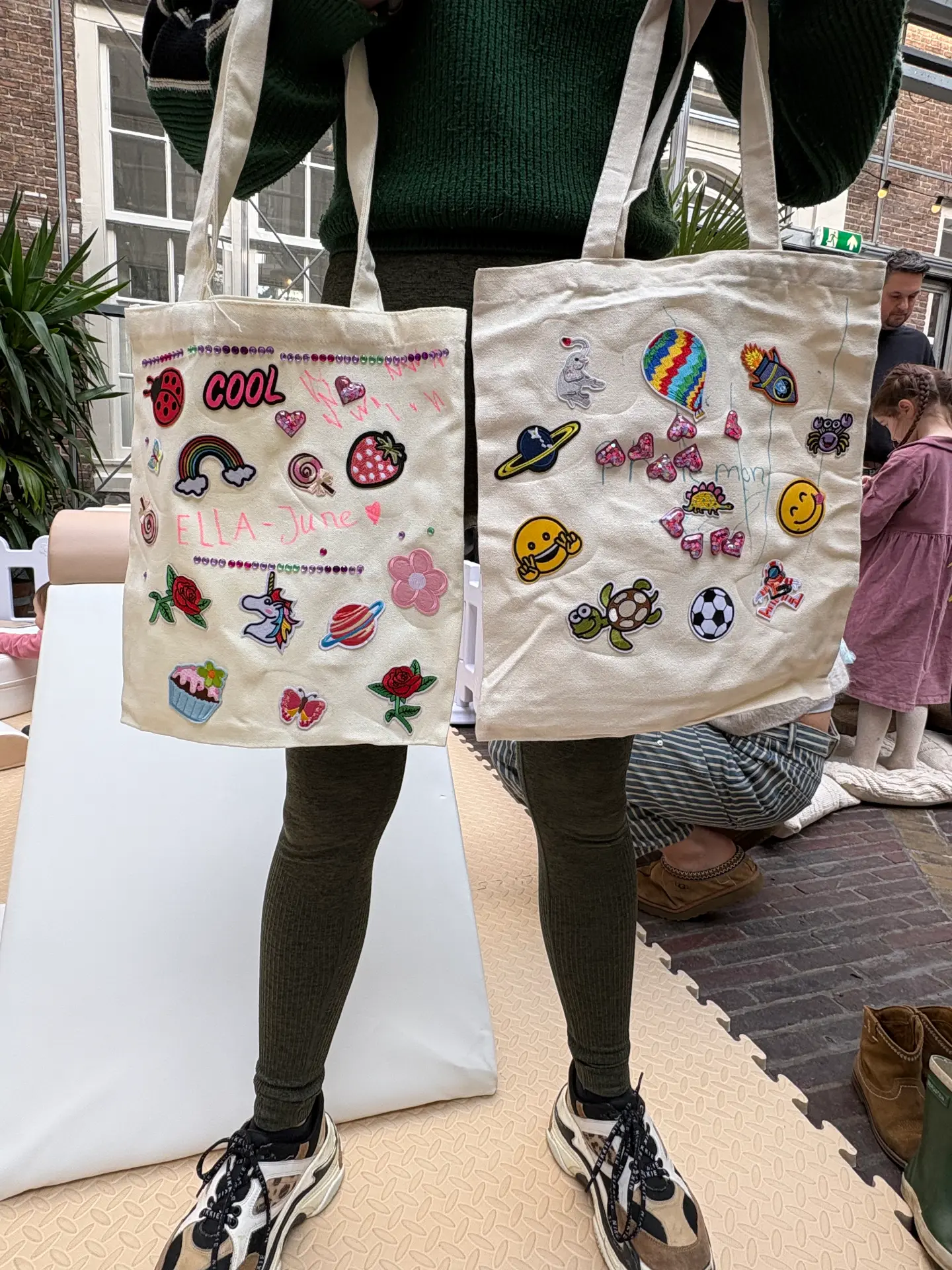 Two tote bags decorated with patches by young guests at a Mini Munchkins workshop