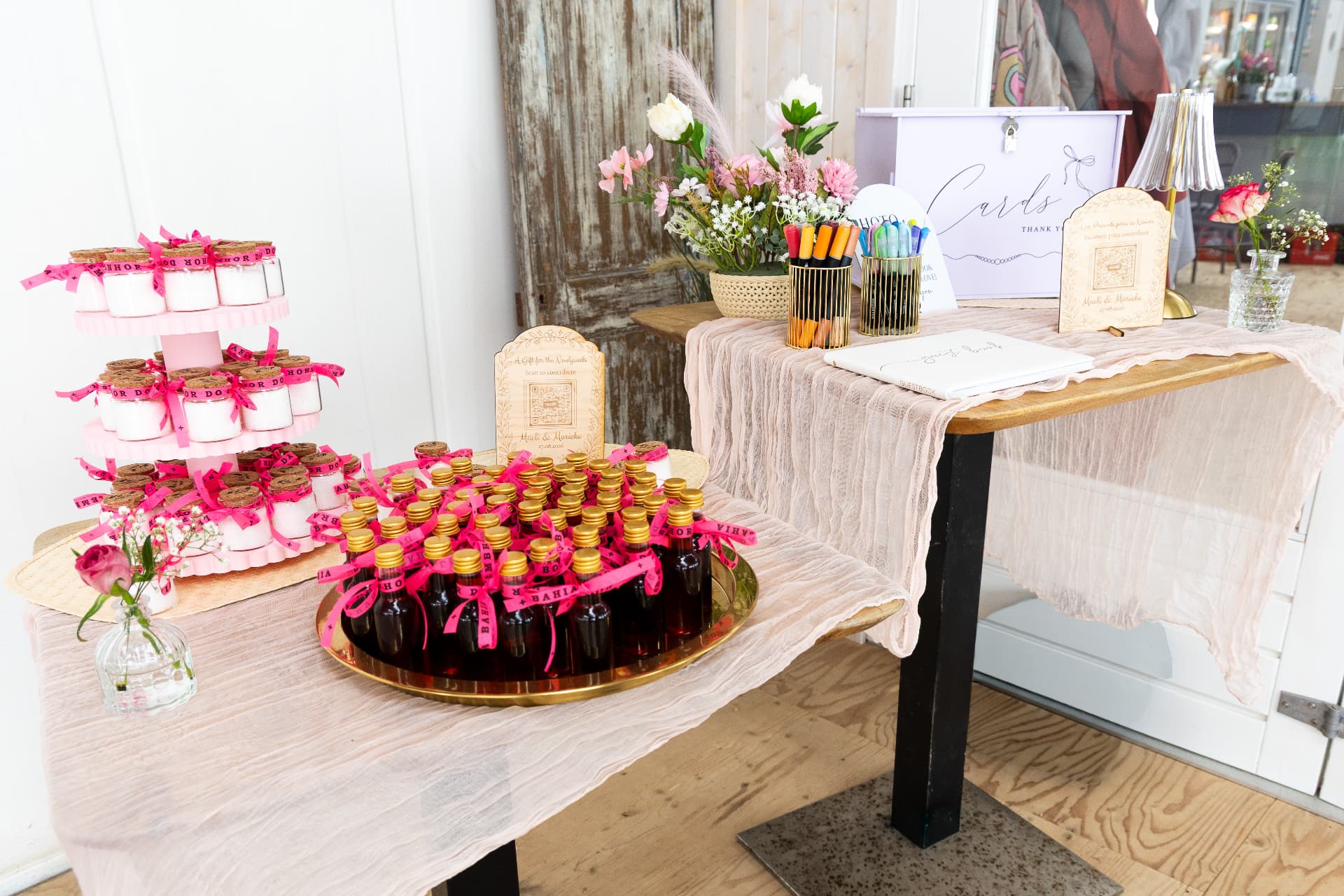 Styled favour table with ribboned jars and bottles on a blush runner